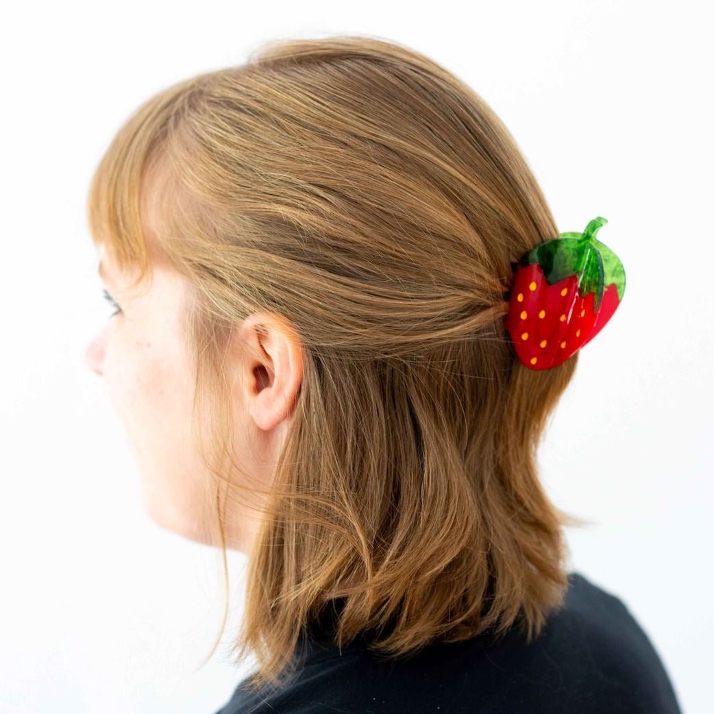 Person with a strawberry-shaped hair clip in their hair on a white background