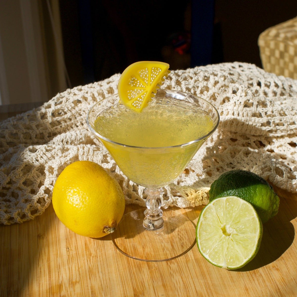 Cocktail in a martini glass with lemon and lime on a wooden surface