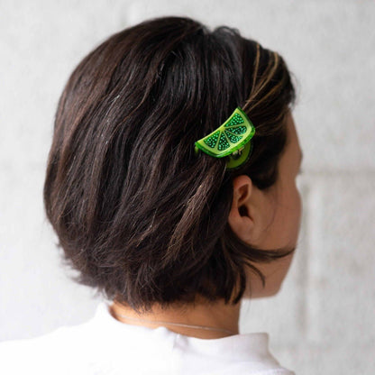 Person with a green decorative hair clip in their hair against a white background
