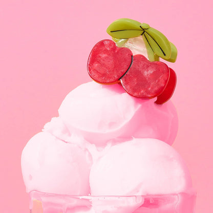 Pink ice cream with cherry and banana toppings on a pink background